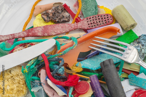 Concept picture food chain plastic waste collected on a beach arranged on a plate with knife and fork ready for eating a meal with plasticizers and hormone poisons