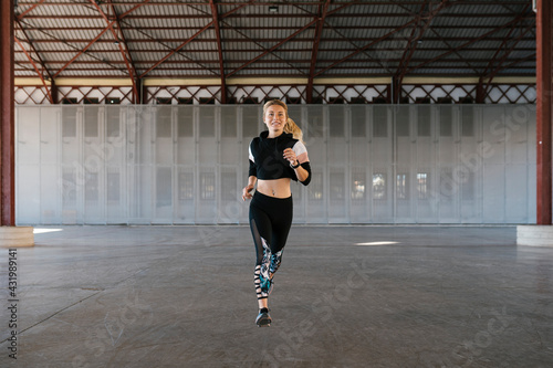 Smiling sportswoman running in health club during training