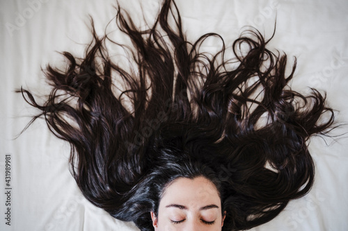 Woman with long hair lying on bed at home photo