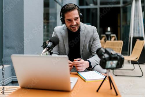 Smiling businessman making vlog on camera while sitting at cafe photo