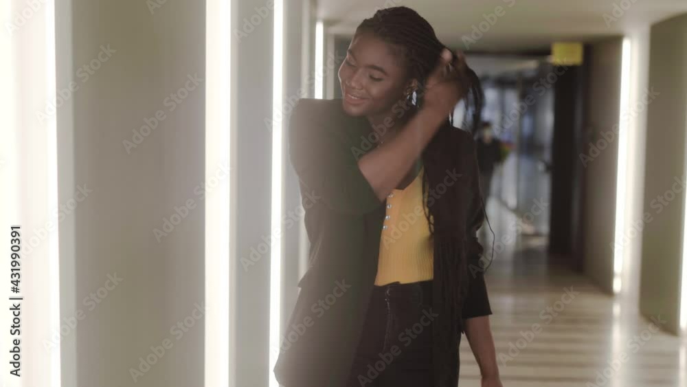 Stylish black woman putting on jacket while walking in hall Stylish black woman putting on jacket while walking in hall