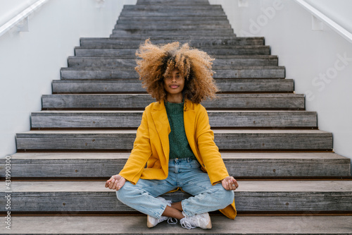 Afro woman in lotus position sitting on staircase photo