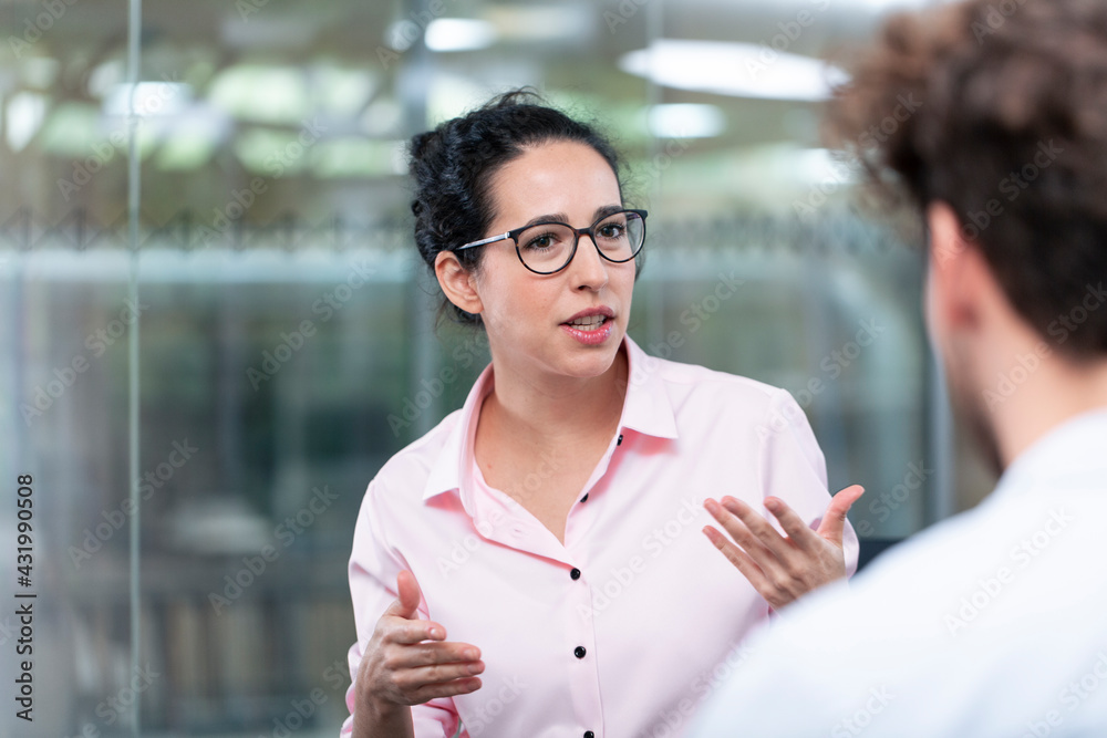© Florian K√ºttler/Westend61 - Female entrepreneur gesturing while talking to male colleague in office