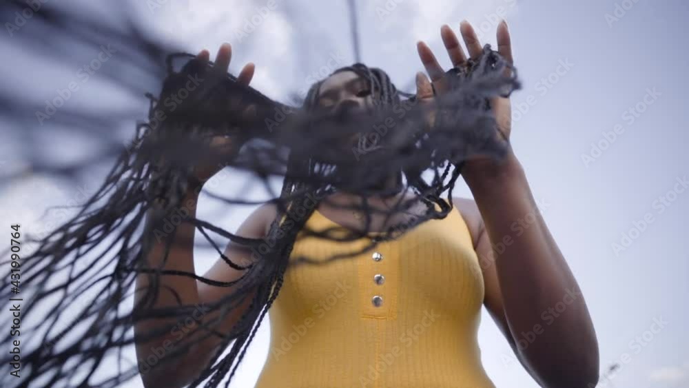 Attractive black woman running long hair through fingers outdoors