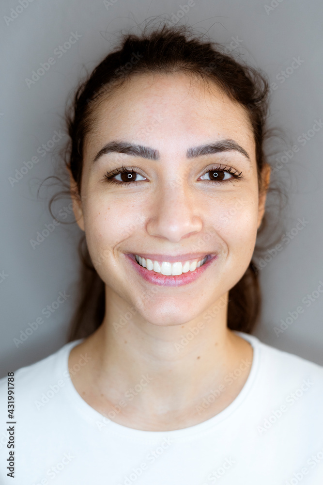 Young woman smiling while standing against gray background Young woman smiling while standing against gray background
