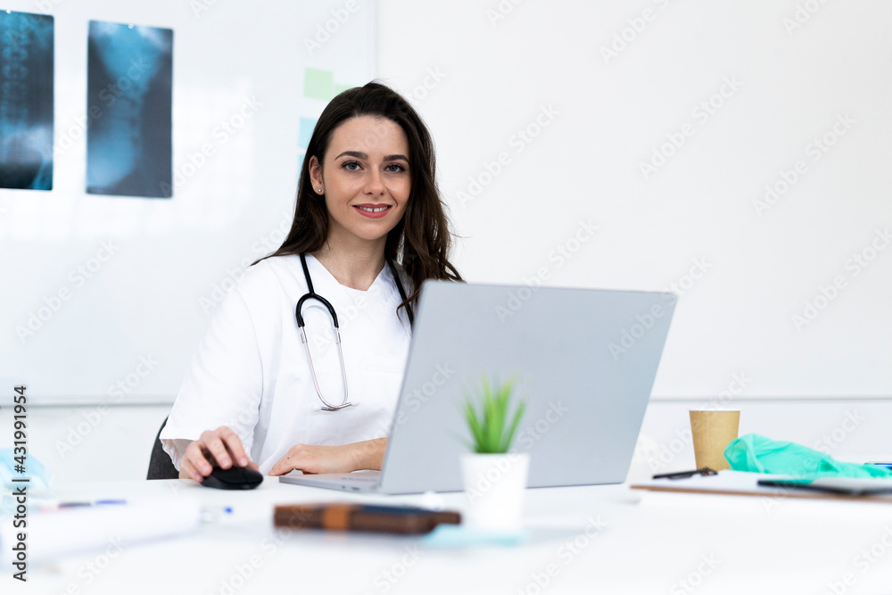 Smiling female doctor using laptop in clinic Smiling female doctor using laptop in clinic