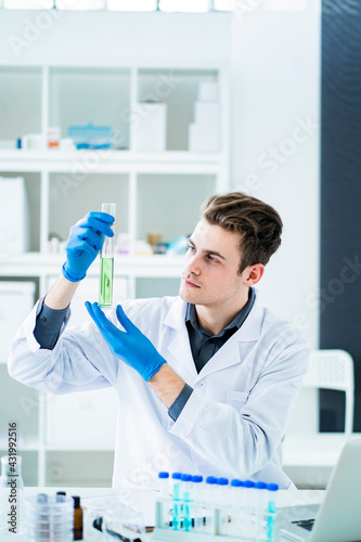 Male scientist holding graduated cylinder at laboratory photo