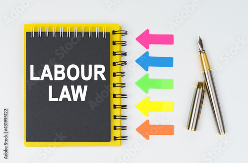 On a white background lies a pen, arrows and a notebook with the inscription - LABOUR LAW photo