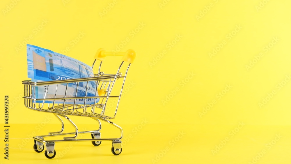 Shopping cart with 2000 rubles banknote on a yellow background, closeup. Black Friday Shopping and Discount Concept Shopping cart with 2000 rubles banknote on a yellow background, closeup. Black Friday Shopping and Discount Concept