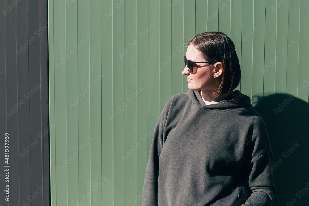 Portrait young woman in agreen sweatshirt and glasses over green background. Sunny autumn summer day, lifestyle concept. Portrait young woman in agreen sweatshirt and glasses over green background. Sunny autumn summer day, lifestyle concept.