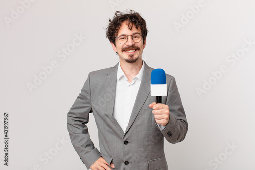 Fotografia young man journalist smiling happily with a hand on hip and confident