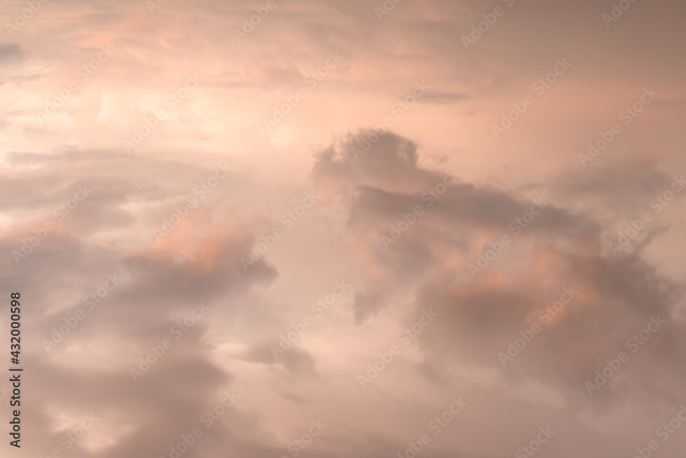 Bright pink orange cloudy sky shot from above after the rain at sunset with a light from the sun on the left side of the frame above the level of clouds in soft colors and tones. High quality photo
