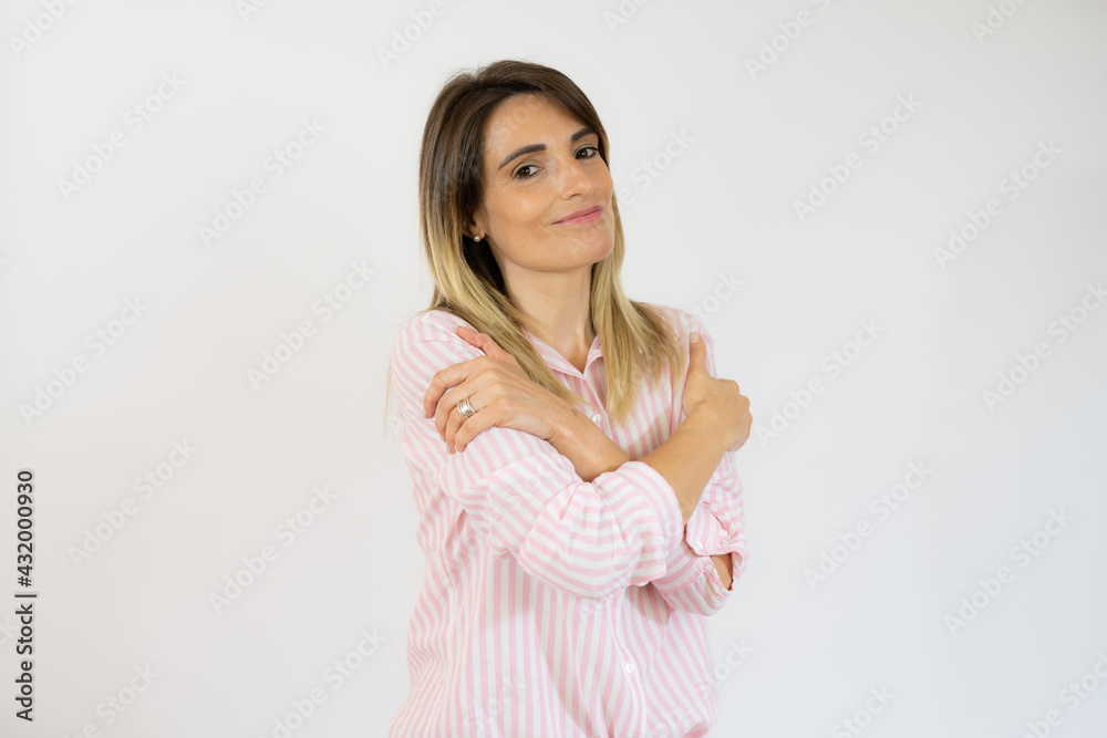 Smiling woman in striped shirt hugging herself isolated over white background. Smiling woman in striped shirt hugging herself isolated over white background.