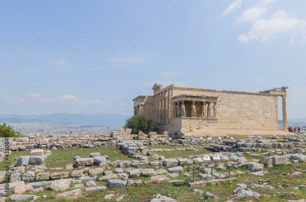 Obraz premium The ancient Erechtheion temple with beautiful Caryatids on Acropolis hill, famous tourist attraction in Athens, Greece, in sunny summer day