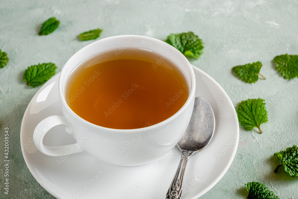 Fresh lemon balm tea in a white cup.