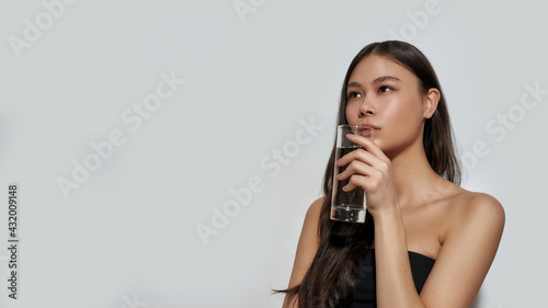 Cute young asian girl drinking water from glass