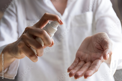 Close up view of woman person using small portable antibacterial hand sanitizer on hands. Coronavirus epidemic prevention concept.