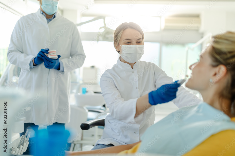 Dentist and patient in dentist office. Dentist with prosthesis in background. Dentist and patient in dentist office. Dentist with prosthesis in background.