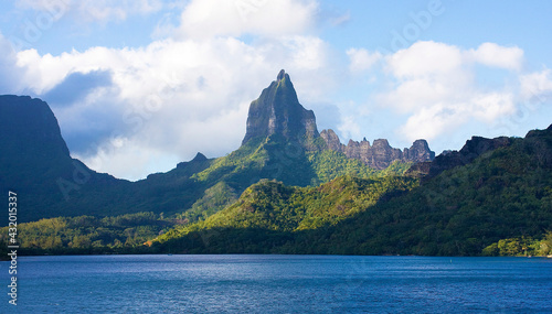Moorea, French Polynesia: Bali Hai peak dominates lush green landscape of Moorea with Pacific in foreground. Billowy clouds.