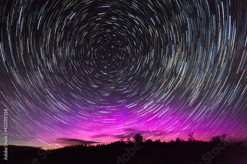 Stars swirl around Polaris, the North Star, as northern lights dance on the northern horizon over Jackson Hole, Wyoming. photo