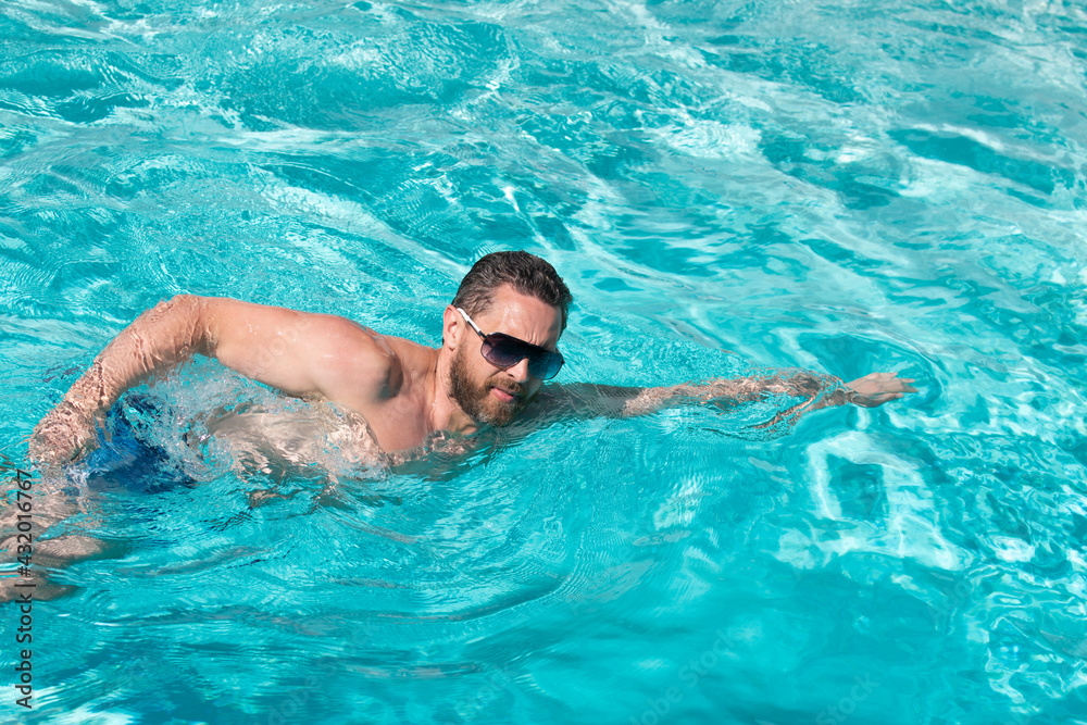 Summer vacation. Man swimming in pool. Summertime pool resort. Active weekend.