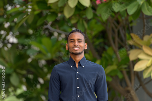 Handsome African businessman outdoors at rooftop garden smiling