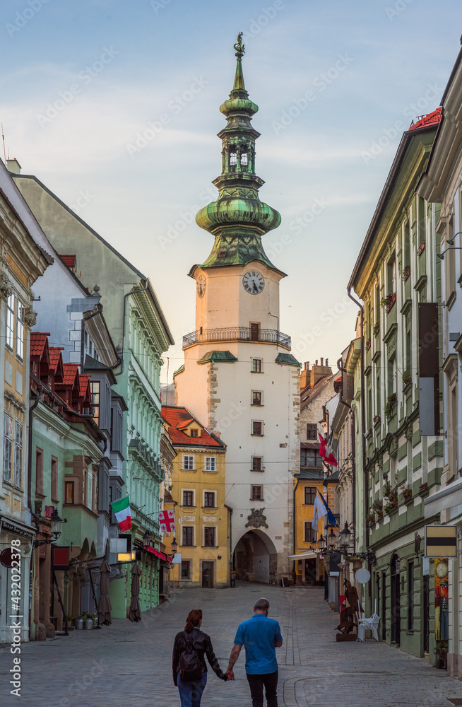 Two People Holding Hands on Empty Michalska Street in Bratislava Old Town During Coronavirus Pandemic with Michael's Tower (Michalska Brana) in Background in Slovakia