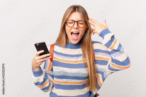 young girl with a cell looking unhappy and stressed, suicide gesture making gun sign photo