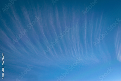High altitude cirrus clouds in the form of stripes against blue sky as background