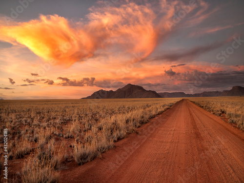 Dirt road in the desert at sunset with a colorful sky, Tiras Mountains, Namibia photo