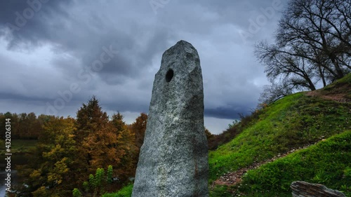 An old stone monument against the background of a river and an autumn forest, in the city of Polotsk .4k. Time lapse 