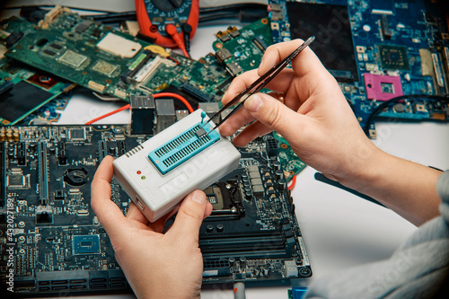 An engineer in a workshop encodes the firmware against the background of the motherboard. photo