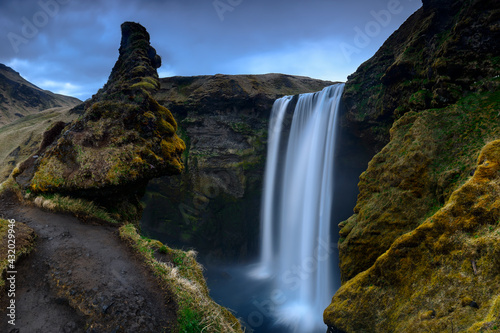 The face of a troll can be seen in the hills above the waterfall Skogafoss in Southern Iceland. photo