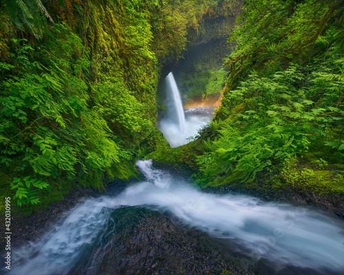 Cascades converge in a steep canyon, leading to a large waterfall below.