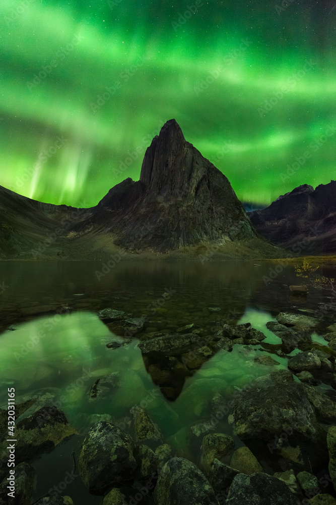 A dazzling aurora blankets the night sky reflected in a lake below in the wilderness of the Ogilvie Mountains, Yukon Territory. A dazzling aurora blankets the night sky reflected in a lake below in the wilderness of the Ogilvie Mountains, Yukon Territory.