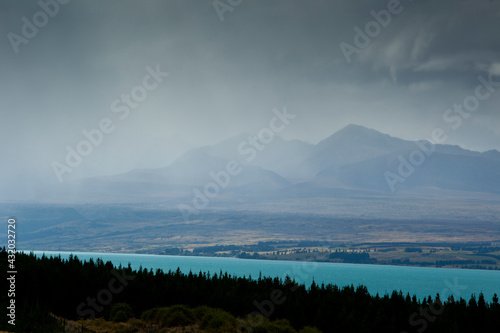 A rainstorm clears from Aoraki / Mt. Cook National Park revealing the aqua-colored glacial melt of Lake Pukaki and the peaks of the Southern Alps in New Zealand's South Island. photo