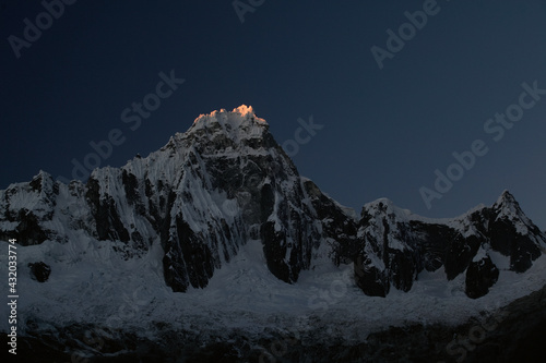 Sunset and the last sliver of light upon Mt. Tralliraju in the Cordillera Blanca in the Andes Mountains of Peru.