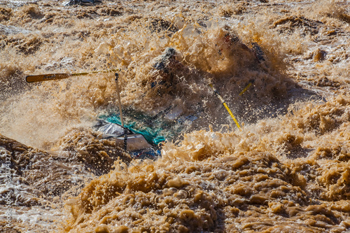 Boatman gets smothered by a giant wave of water as he rows his raft through the notoriously huge V wave in Lava Falls Rapid on the Colorado River. Grand Canyon National Park. photo