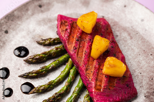 Beetroot marinated salmon with asparagus and pineapple. photo