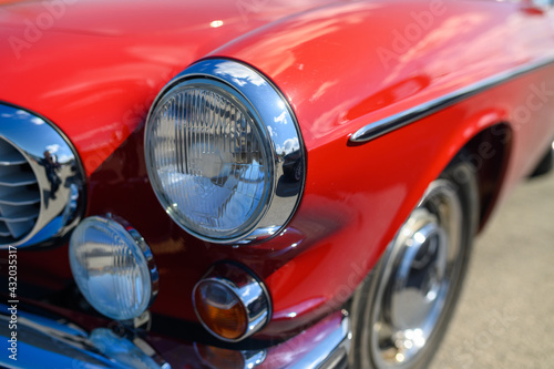 Detail of chrome and headlamps of classic red colour vintage car © Oskars
