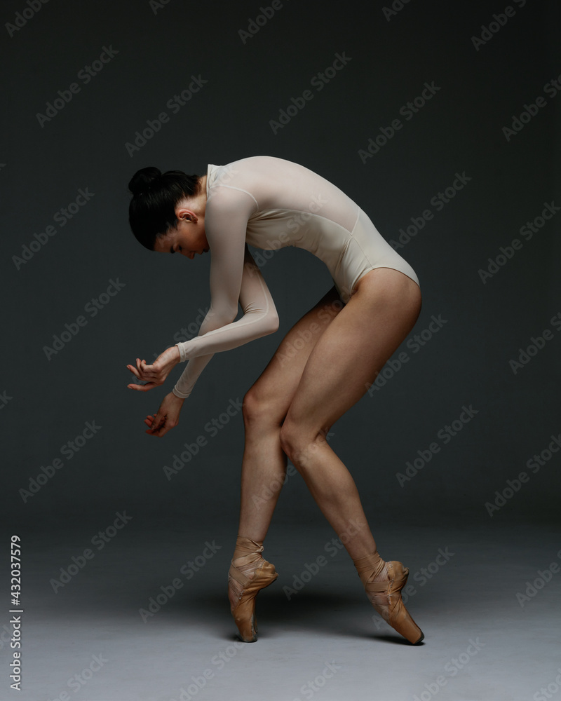Young beautiful skinny ballerina is posing in studio