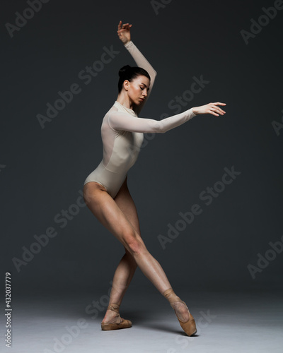 Young beautiful skinny ballerina is posing in studio