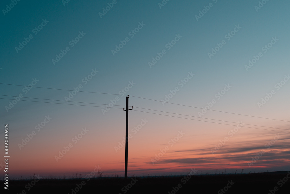 Electric pole with wires at sunset.