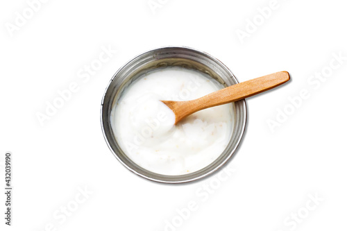 metal bowl of cream or yogurt isolated on white background with wooden spoon