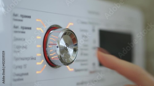Woman's hand turning on and off the switch of the washing machine