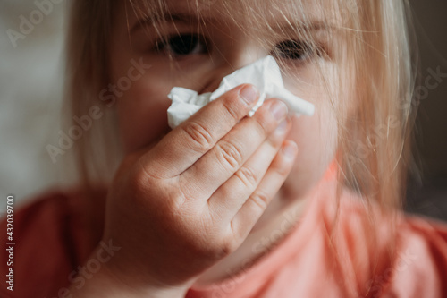 Toddler girl blowing her nose with a tissue