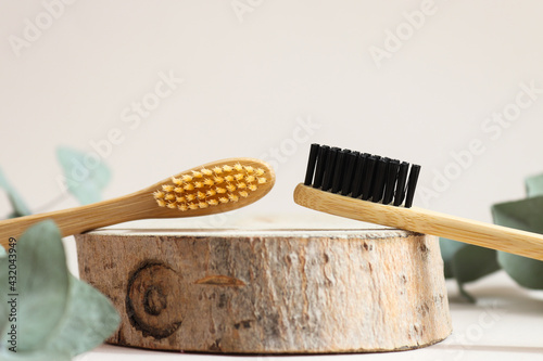 A pair of eco-friendly bamboo toothbrushes on a wood cut close-up. Oral hygiene and zero waste concept. Selective focus