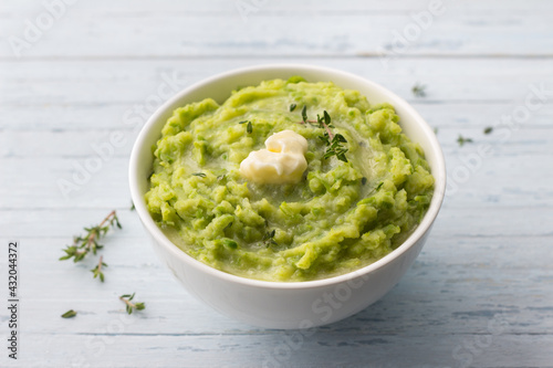 Delicate mashed potatoes with green peas, flavored with butter, spices and thyme on a light blue background. delicious homemade food	