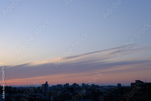 兵庫県神戸市東灘区の高層マンションの上層階からの夜明け。大阪生駒山から太陽が昇り、あたりはオレンジ色に染まり、ビル群がシルエットで浮かぶ。 © 宮岸孝守