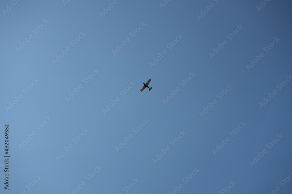Small black plane on a background of blue sky.